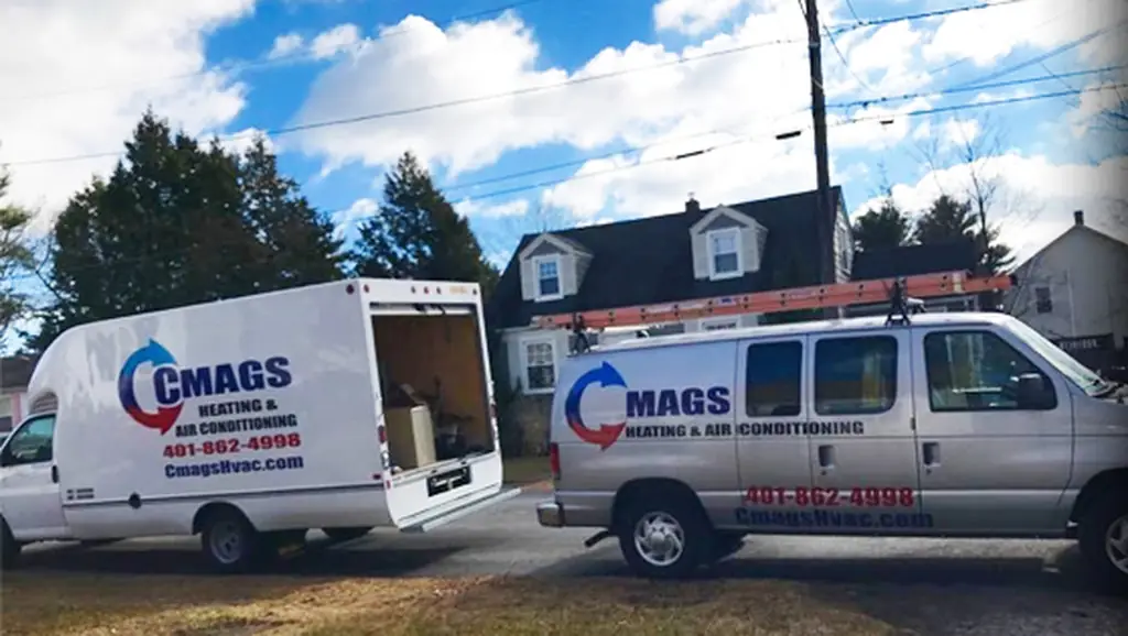 Two Cmags Heating and Air Conditioning vans parked on a residential street in Warwick, Rhode Island, ladder racked on the roof